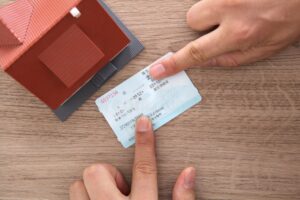 main tenant une maison miniature et un billet