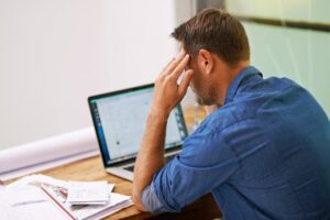 personne reflechissant avec documents financiers et ordinateur